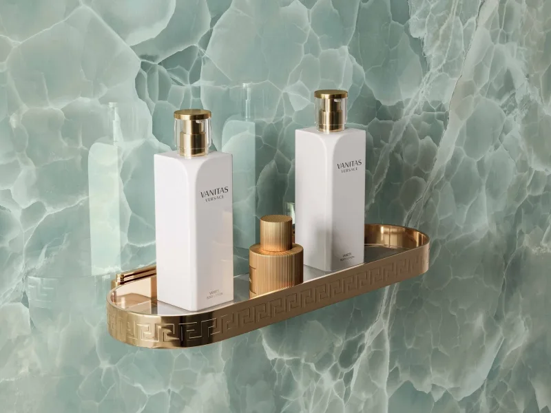 A gold Greek shelf, 40 cm, holding toiletries against a green onyx wall