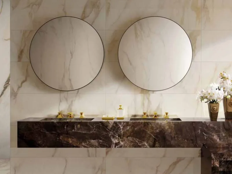 Round mirrors above a brown marble vanity, gold Superbe fittings