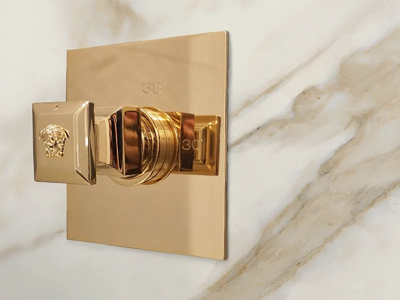 A gold Superbe thermostatic mixer with the Medusa medallion
