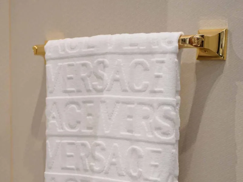 A gold Superbe towel rail with a Versace towel